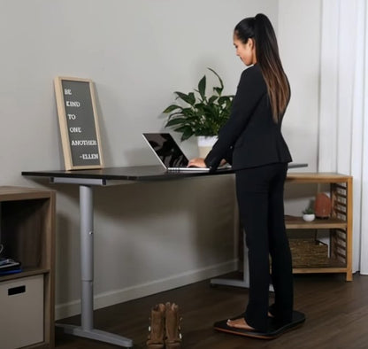 Person som står på balansbräda vid skrivbord – aktiverar bål och förbättrar hållning