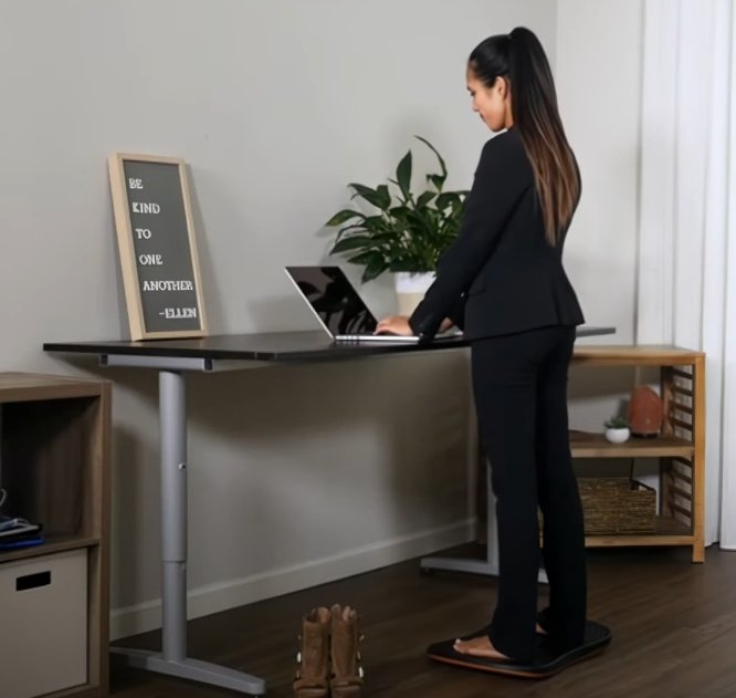 Person som står på balansbräda vid skrivbord – aktiverar bål och förbättrar hållning